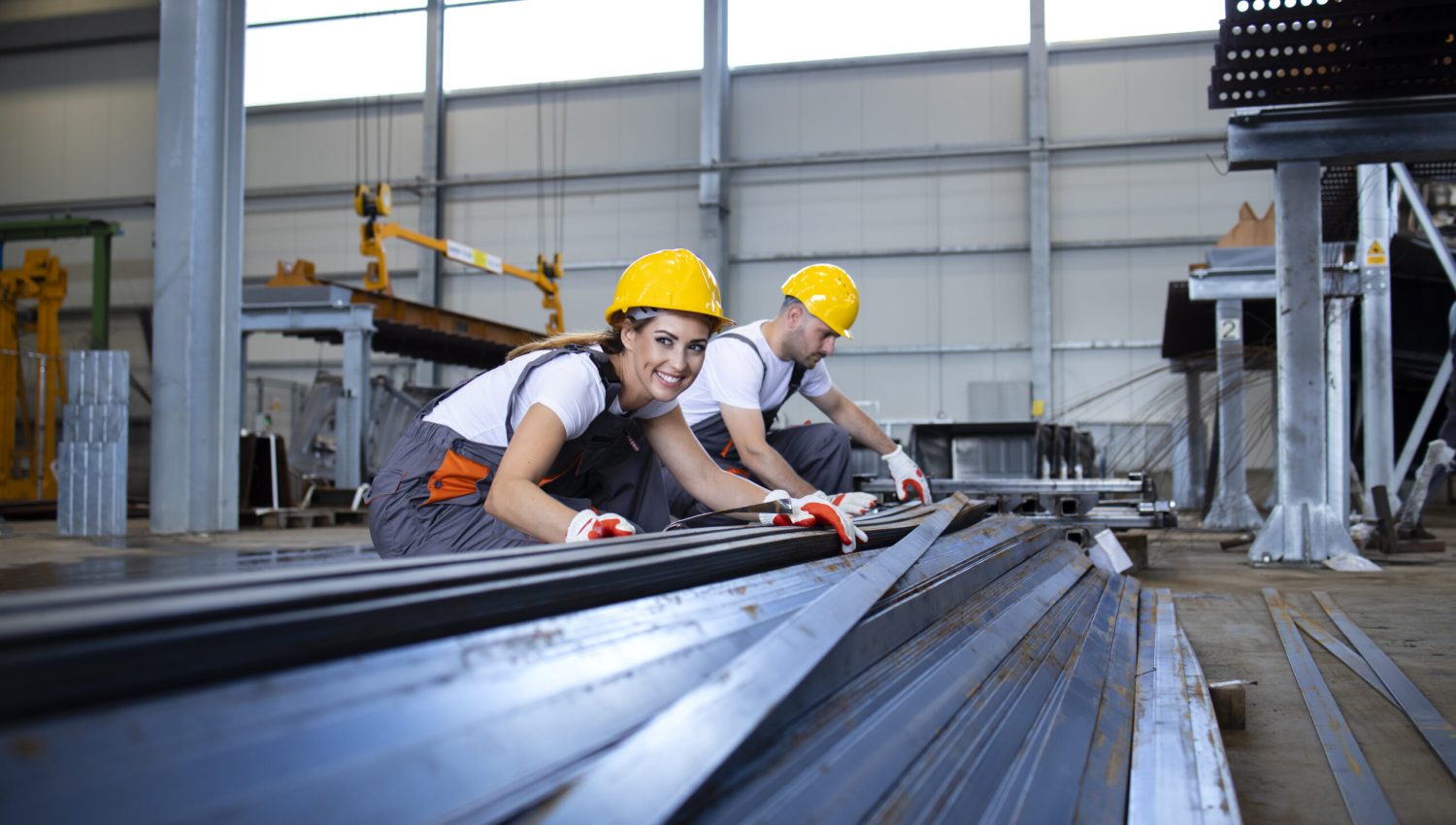 Industrial workers working in factory hall with metal.